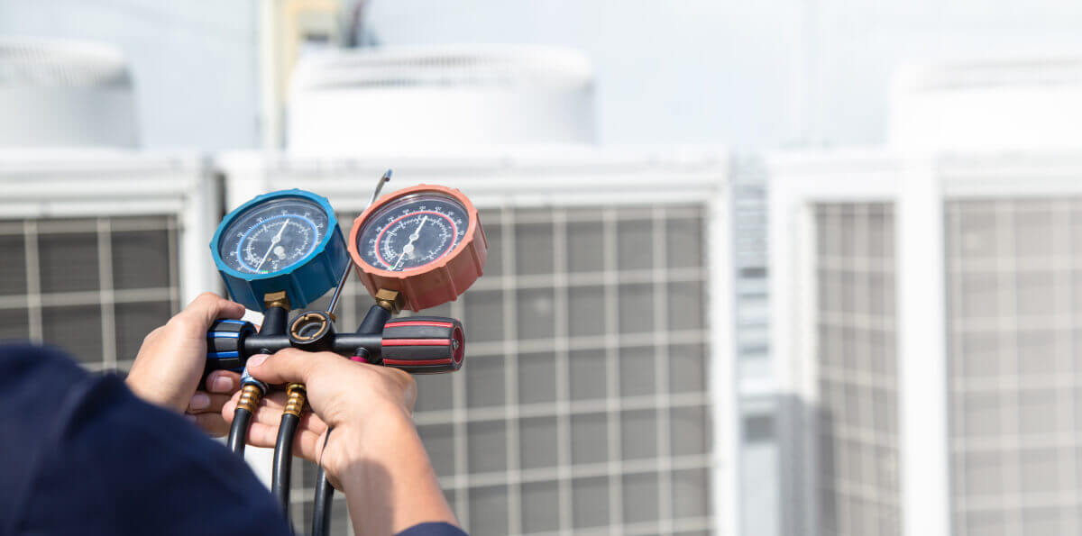 A man demonstrates refrigerant management in HVAC systems by holding a thermometer and a hose near a heat pump.