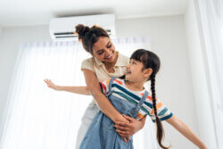 Mum hugging her daughter in front of air conditioning in los angeles